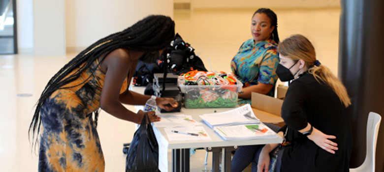 A community member engages with SchoolTalk staff at an in-person registration table for an event.